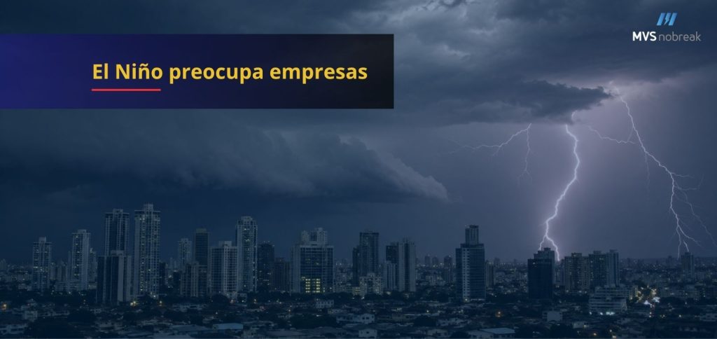 Imagem em formato horizontal com temática corporativa e climática. Ao fundo, uma paisagem urbana composta por diversos prédios altos sob um céu carregado de nuvens escuras. No lado direito da imagem, um raio intenso corta o céu durante uma forte tempestade, iluminando parcialmente os edifícios e reforçando a sensação de risco e instabilidade.
Na parte superior esquerda, há uma faixa retangular azul-escura semitransparente. Sobre ela, em letras grandes e amarelas, está escrito: "El Niño preocupa empresas". Abaixo do título, uma pequena linha vermelha serve como elemento de destaque visual.
No canto superior direito aparece o logotipo da MVS Nobreak em tons de azul e branco.
A composição transmite uma sensação de alerta, prevenção e continuidade operacional diante de eventos climáticos extremos que podem causar quedas de energia e impactar empresas.